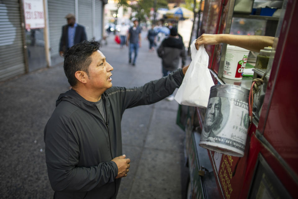 Ecuadorian immigrant Neptali Chiluisa buys fast food on truck in the borough of Bronx on Thursday, Oct. 21, 2021, in New York. Nearly six months ago, the Biden administration established a “dedicated docket” for families, many seeking asylum, in New York and 10 other cities, including Boston, San Francisco, Miami and El Paso, Texas. Chiluisa crossed the border in June in Arizona and was detained for a week with his 14-year-old son, leaving behind his wife and three other children in Ecuador. (AP Photo/Eduardo Munoz Alvarez)