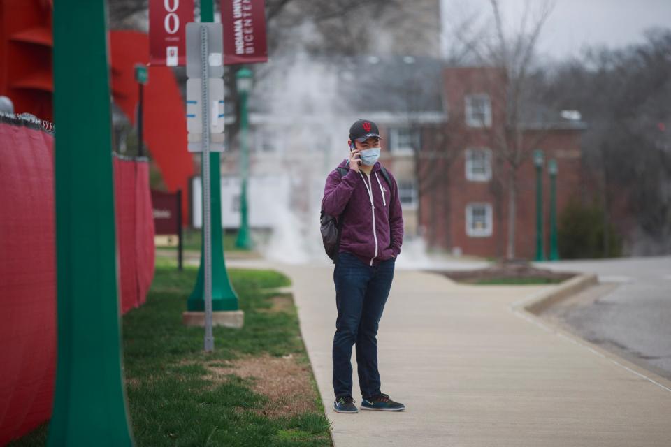 An international student at Indiana University waits for a bus on March 20, after the campus shut down due to the pandemic. The student said he was stuck in the U.S. as the coronavirus shut down travel around the world.