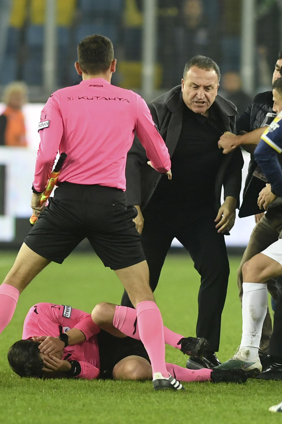 Referee Halil Umut Meler holds his face as he lies on the ground after being punched by MKE Ankaragucu president Faruk Koca, center right, at the end of the Turkish Super Lig soccer match between MKE Ankaragucu and Caykur Rizespor in Ankara, Monday, Dec. 11, 2023. The Turkish Football Federation has suspended all league games in the country after a club president punched the referee in the face at the end of a top-flight match. Koca was arrested Tuesday, Dec. 12, 2023, along with two other people on charges of injuring a public official following questioning by prosecutors. (Abdurrahman Antakyali/Depo Photos via AP)