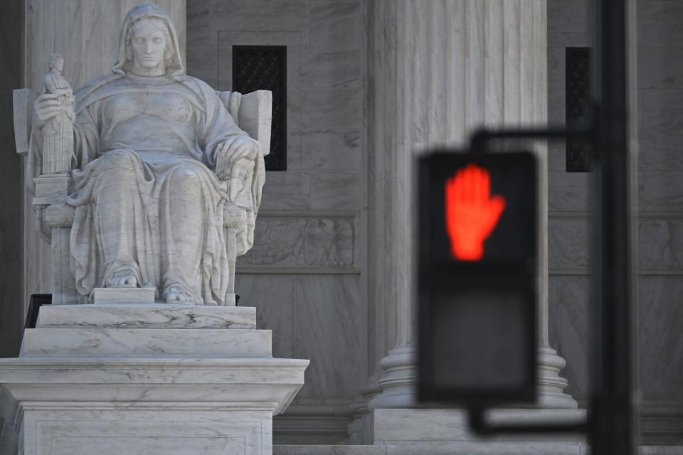 A stop sign as seen on traffic light near a statue at the Supreme Court in Washington, DC, February 26, 2024.