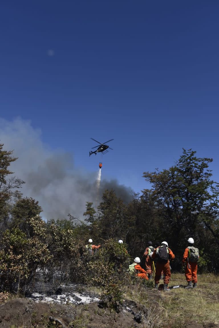 Los brigadistas trabajan en conjunto con helicópteros hidrantes