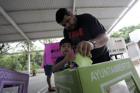 A man casts his ballot with the help of his son at a polling station during mid-term elections in the town of Santiago, state of Nuevo Leon, June 7, 2015. REUTERS/Daniel Becerril