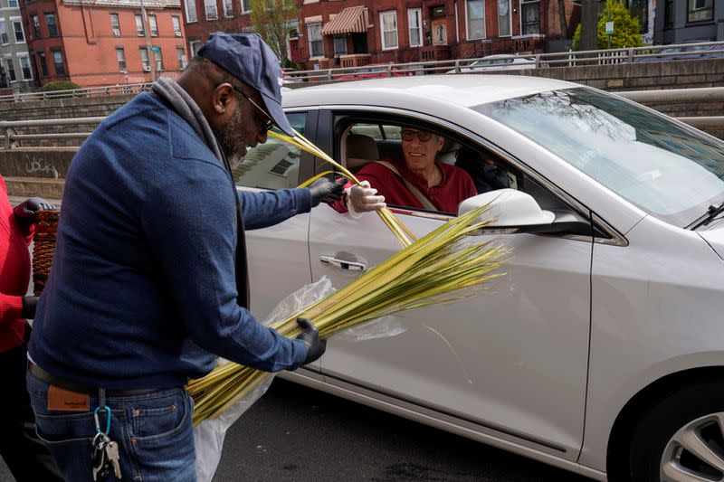 Palm fronds are distributed to the faithful at their cars on Palm Sunday in Washington