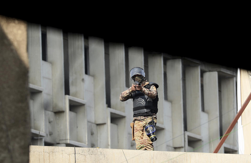 An Iraqi security forces member holds a teargas gun as they try to disperse anti-government protesters during ongoing protests in downtown Baghdad, Iraq, Friday, Nov. 15, 2019. (AP Photo/Hadi Mizban)