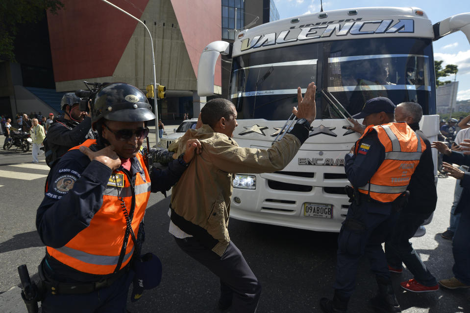 An opposition supporter argues for traffic cops to stop blocking buses carrying opposition lawmakers to the National Assembly in Caracas, Venezuela, Tuesday, Jan. 7, 2020. Opposition leader Juan Guaidó and lawmakers who back him pushed their way into the legislative building on Tuesday following an attempt by rival legislators to take control of the congress, and declared Guaidó the president of the only opposition-controlled institution. (AP Photo/Matias Delacroix)