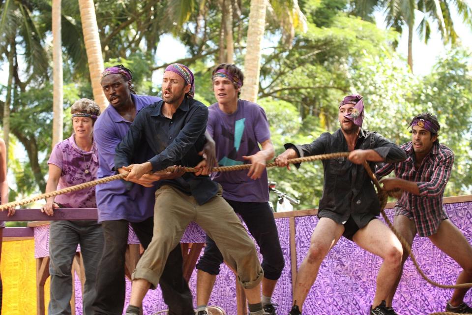 Survivor players wearing purple tugging on a rope during a challenge