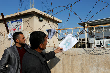 FILE PHOTO: People look at pictures of victims, after a ferry sank in the Tigris river, outside a morgue in Mosul, Iraq March 22, 2019. REUTERS/Khalid al-Mousily/File Photo