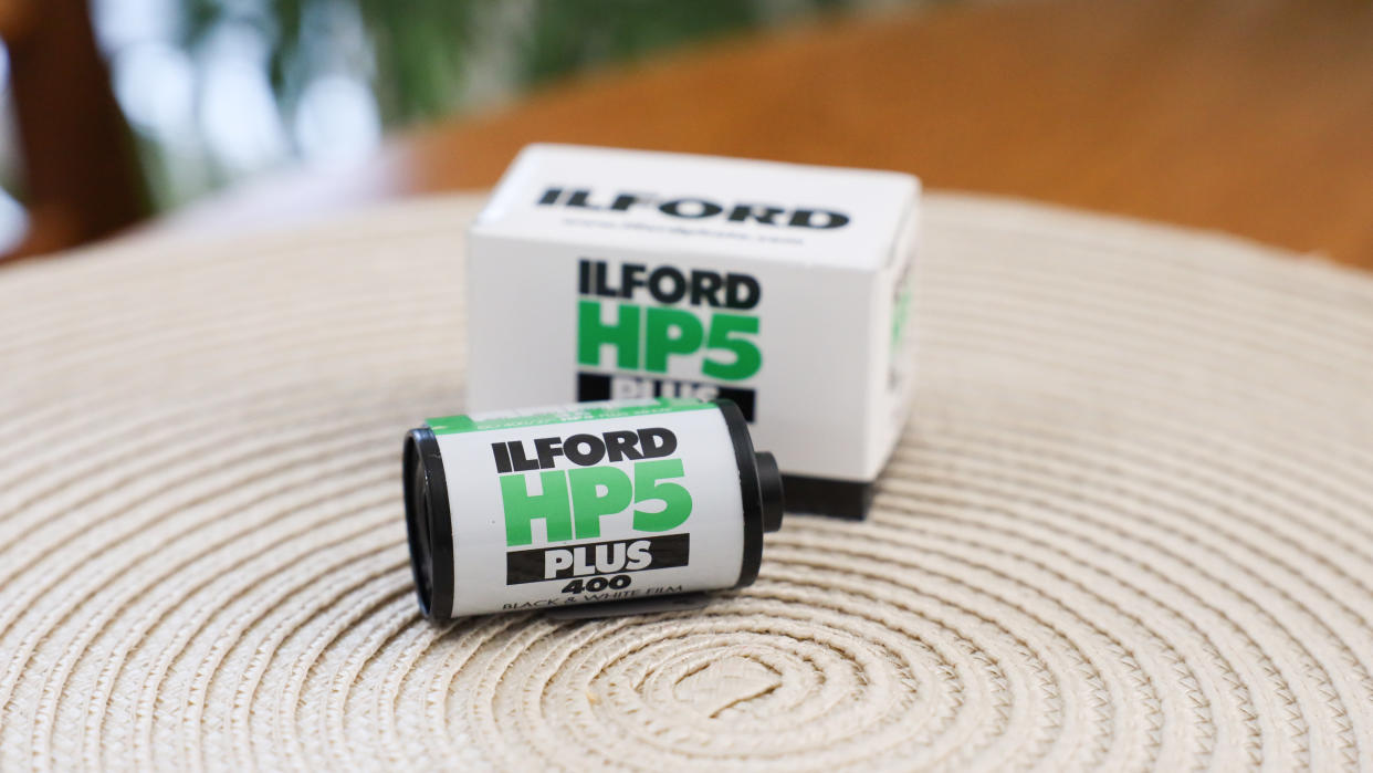  Ilford HP5 Plus 35mm film canister on a table next to it packaging box. 