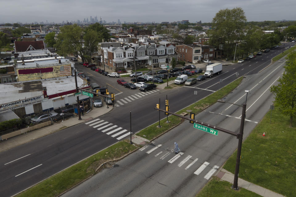 A pedestrian crosses at the eastbound side of Roosevelt Avenue on at the Banks Way crosswalk, Thursday, May 12, 2022, in Philadelphia. Roosevelt Boulevard is an almost 14-mile maze of chaotic traffic patterns that passes through some of the city's most diverse neighborhoods and Census tracts with the highest poverty rates. Driving can be dangerous with cars traversing between inner and outer lanes, but biking or walking on the boulevard can be even worse with some pedestrian crossings longer than a football field and taking four light cycles to cross. (AP Photo/Julio Cortez)