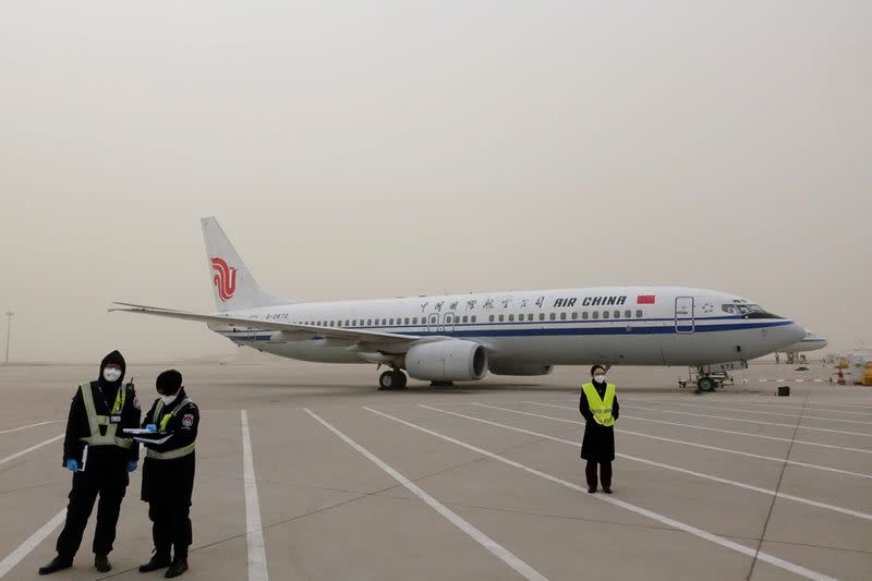 Staff members stand on the tarmac of Beijing Capital International Airport as the city is hit by a sandstorm, in Beijing