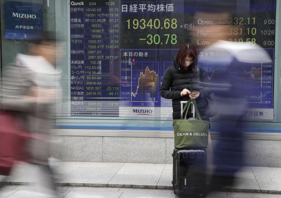 People walk by an electronic stock board of a securities firm in Tokyo, Friday, Feb. 24, 2017. Asian markets slipped in muted trading Friday amid worries over U.S. trade policies that may affect regional economies. A stronger yen weighed on Japan's exporters. (AP Photo/Koji Sasahara)