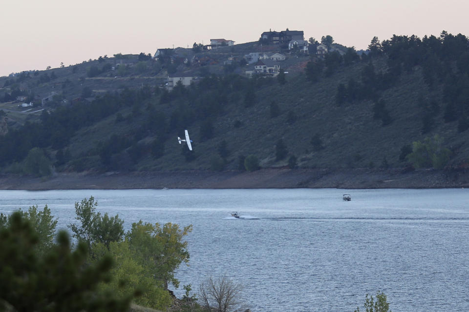 In this image provided by Stephanie Stamos, a small plane flies over boats in a Northern Colorado reservoir before it crashed near Fort Collins Sunday Sept. 11, 2022. Law-enforcement officials said two people in the single-engine plane survived the crash with minor injuries. Photographer Stephanie Stamos who was at the reservoir outside Fort Collins took photos of the plane fly near boaters and said the plane looked unstable and that the aircraft's wheels almost touched a boat. (Stephanie Stamos via AP)