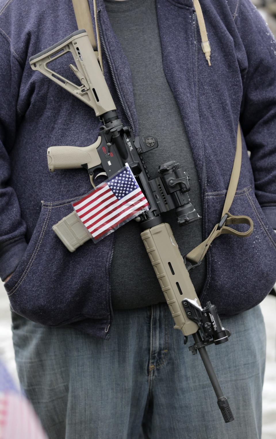 FILE - In this Saturday, Feb. 23, 2013 file photo, a gun-rights activist carries his rifle decorated with a U.S. flag during a "National Day of Resistance" rally at the Utah State Capitol in Salt Lake City, Utah