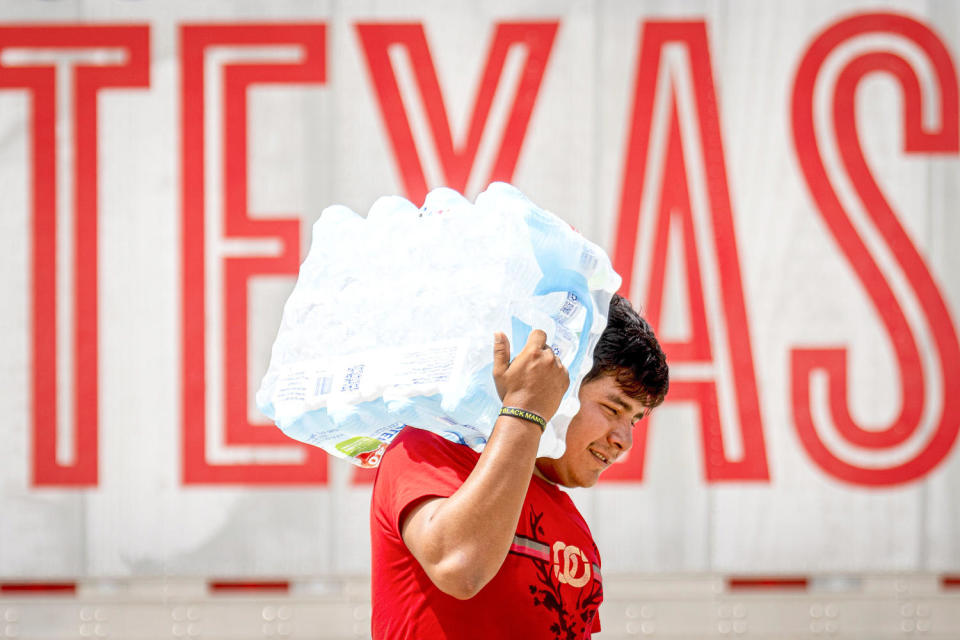 A man carries water on his shoulder. (Jason Fochtman / Houston Chronicle via AP)