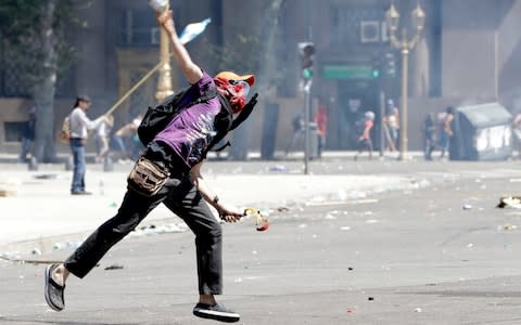 A demonstrator throws a bottle at police during a protest - Credit: Natacha Pisarenko /AP