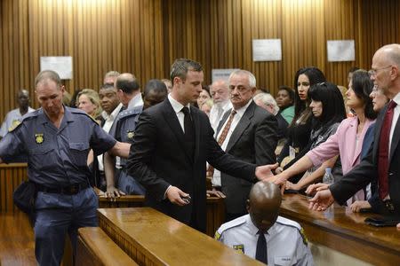 South African Olympic and Paralympic track star Oscar Pistorius holds the hands of family members after being sentenced at the North Gauteng High Court in Pretoria October 21, 2014. REUTERS/Herman Verwey/Pool