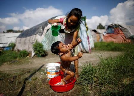 A girl showers her sister at the displacement camp for earthquake victims at Chuchepati in Kathmandu, Nepal, September 19, 2016. Picture taken September 19, 2016. Thomson Reuters Foundation/Navesh Chitrakar