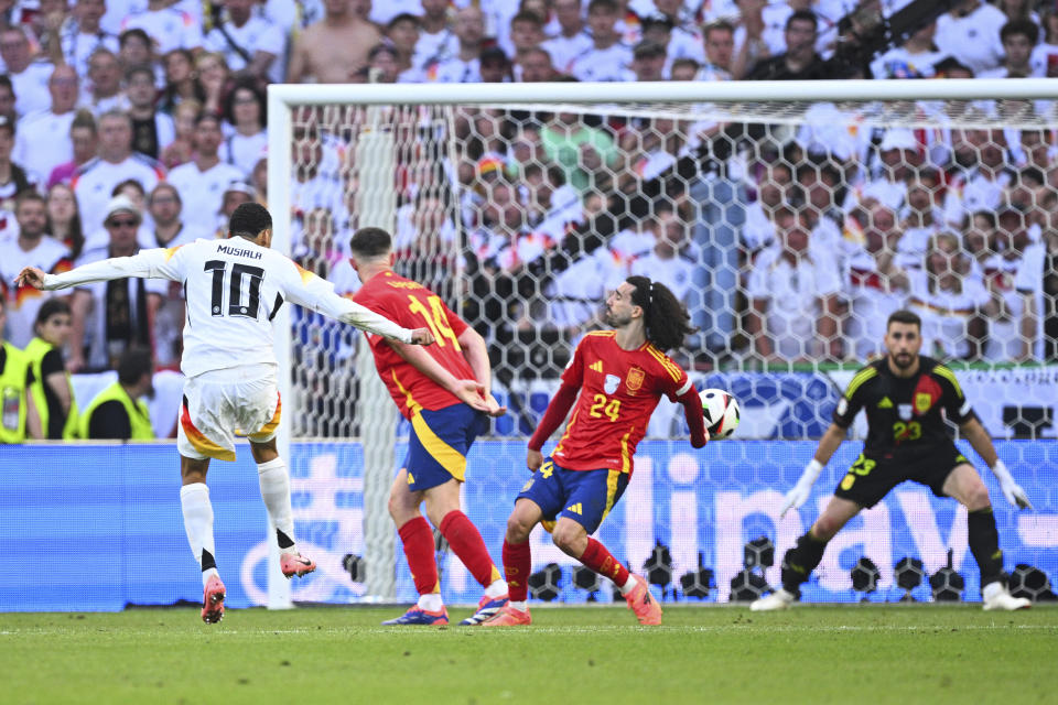 Germany's Jamal Musiala, left, shoots sthe ball against Spain's Marc Cucurella, center, during a quarterfinal match between Germany and Spain at the Euro 2024 soccer tournament in Stuttgart, Germany, Friday, July 5, 2024. (Tom Weller/dpa via AP)