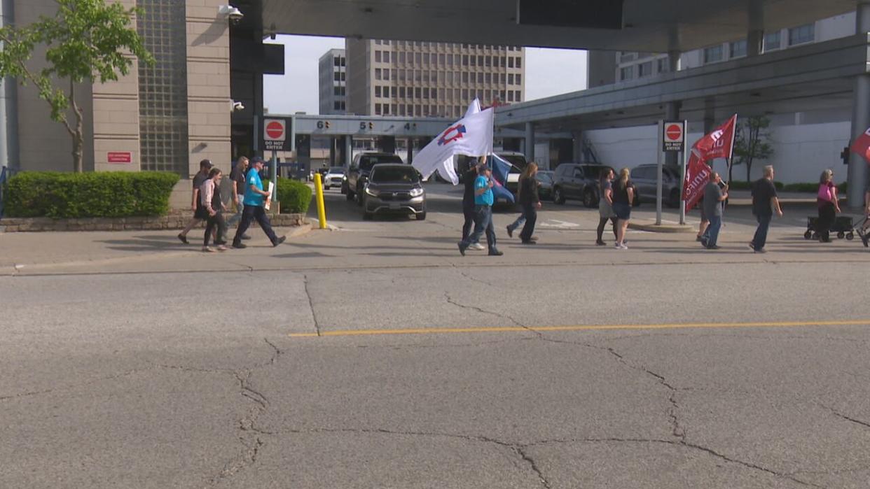 Cars wait to exit the Detroit-Windsor Tunnel while members of the Public Service Alliance of Canada march past on Monday May 13, 2024. (Dale Molnar/CBC - image credit)