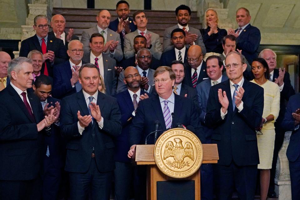 Mississippi Republican Gov. Tate Reeves, center, receives applause from House Speaker Jason White, R-West, left, and Republican Lt. Gov. Delbert Hosemann, right, as well as a bipartisan group of legislators, for pursing a package of state incentives to support a plan by Amazon Web Services to build two data processing centers in the central part of the state, Thursday, Jan. 25, 2024, during the celebratory announcement at the Mississippi Capitol in Jackson, Miss.