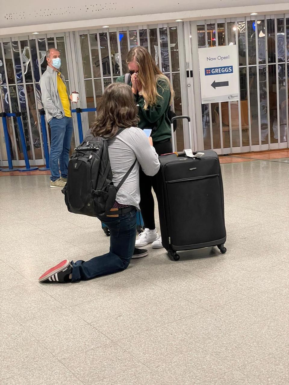 Josh Atkinson, 32 of England, reads from a poem he wrote for his girlfriend, Alexis Olson, 30 of Minnesota, while he proposes at the Manchester Airport. The couple had been separated by travel bans for about a year and a half.