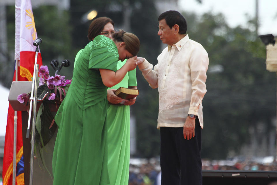 Philippine Vice President-elect Sara Duterte, left, places the hands of her father, outgoing Philippine President Rodrigo Duterte, on her forehead as a sign of respect during her oath taking rites as vice president in her hometown in Davao city, southern Philippines on Sunday June 19, 2022. Duterte clinched a landslide electoral victory despite her father's human rights record that saw thousands of drug suspects gunned down. (AP Photo/Manman Dejeto)