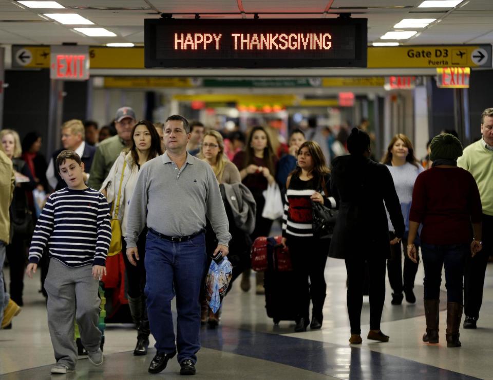 Travelers walk under a sign reading "Happy Thanksgiving" at LaGuardia Airport in New York, Tuesday, Nov. 26, 2013. A winter storm system that hit parts of Arkansas, Oklahoma and Texas swept toward the densely populated East Coast on Tuesday, threatening to disrupt the plans of travelers ahead of the long Thanksgiving holiday weekend. (AP Photo/Seth Wenig)