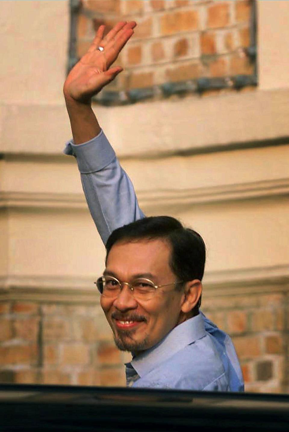 FILE - Then ousted Malaysian Deputy Prime Minister Anwar Ibrahim waves to photographers when he arrives at the federal courthouse in Kuala Lumpur for his trial on sodomy charges on June 8, 1999. With a battle cry of “We Can,” reformist opposition leader Anwar Ibrahim has launched what could be his last chance to fulfill a 2-decade-long quest to become Malaysia’s leader in Nov. 19, 2022, general elections. (AP Photo/Vincent Thian, File)