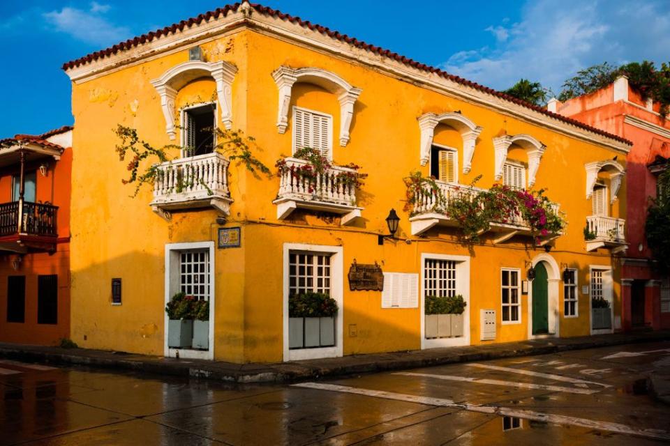 <p>A saturated orange building with bright white balconies and verdant vines.</p>