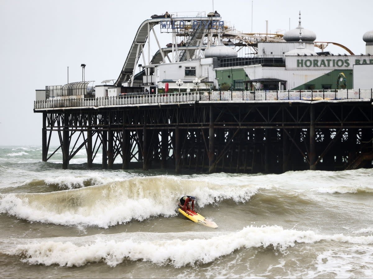 A person attempts to surf next to the Palace Pier in Brighton (AFP)