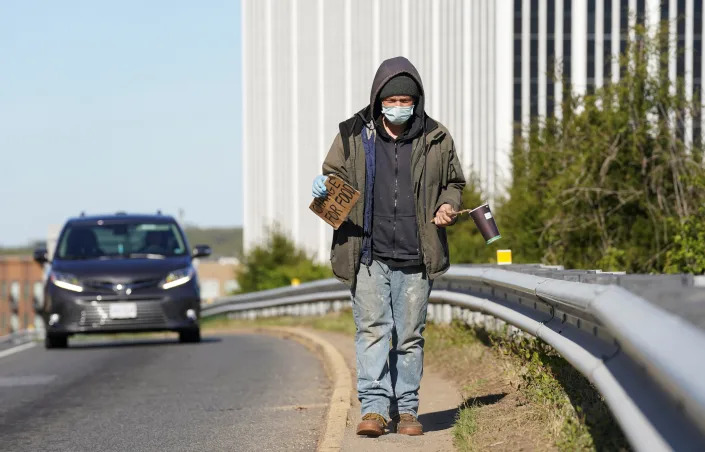 Equipped with a surgical glove, a face mask and a long stick, a jobless man named Paul panhandles at an intersection in Falls Church, Virginia, April 3, 2020. REUTERS/Kevin Lamarque