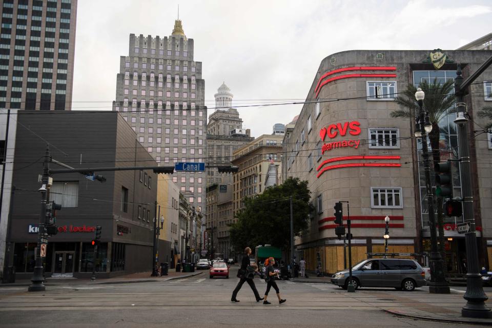 People walk down Canal Street past a boarded up CVS Pharmacy in New Orleans (AFP via Getty Images)