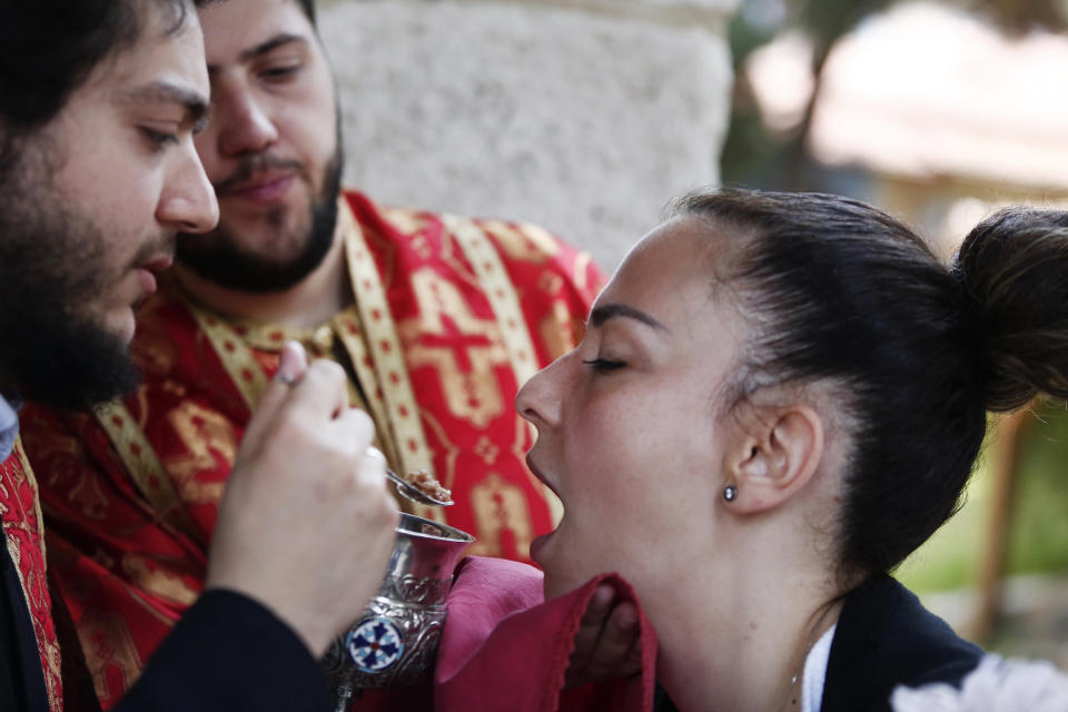 In this Sunday, May 24, 2020, photo, a Greek Orthodox priest distributes Holy Communion during Sunday Mass at a church, in the northern city of Thessaloniki, Greece, using a traditional shared spoon. Contrary to science, the Greek Orthodox Church insists it is impossible for any disease, including the coronavirus, to be transmitted through Holy Communion. (AP Photo/Giannis Papanikos)