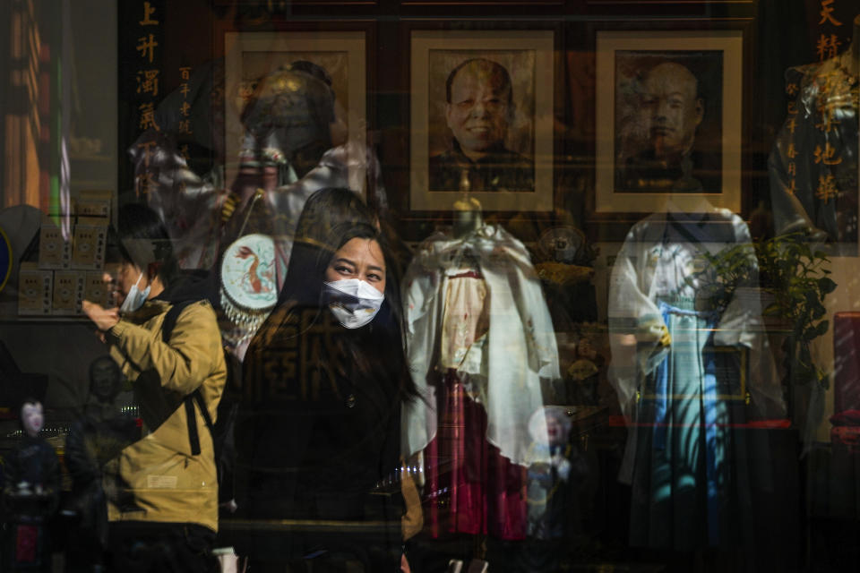 Una mujer con mascarilla se refleja en el ventanal de una tienda que vende trajes tradicionales chinos el miércoles 1 de marzo de 2023 en una calle comercial turística en Beijing. La agenda del presidente chino Xi Jinping para la reunión anual del órgano legislativo ceremonial: Reactivar la maltrecha economía animando a los consumidores a gastar ahora que han finalizado los severos controles antivirus. (AP Foto/Andy Wong)