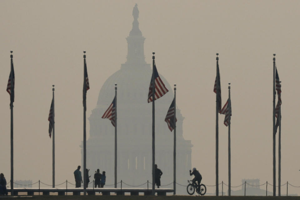 WASHINGTON, DC - JUNE 07: Tourists walk around the base of the Washington Monument as wildfire smoke casts a haze of the U.S. Capitol on the National Mall on June 07, 2023 in Washington, DC. Air pollution alerts were issued across the United States due to smoke from wildfires that have been burning in Canada for weeks. (Photo by Chip Somodevilla/Getty Images)