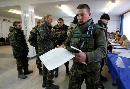 Members of Ukrainian government forces, who are taking part in a military operation in eastern Ukraine, visit a polling station during a parliamentary election in the town of Kramatorsk, October 26, 2014. REUTERS/Vasily Fedosenko
