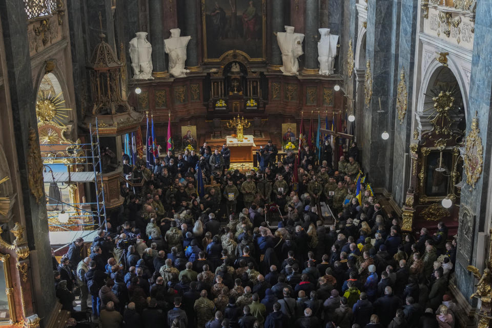 People attend a funeral ceremony for four of the Ukrainian military servicemen, who were killed during an airstrike in a military base in Yarokiv, in a church in Lviv, Ukraine, Tuesday, March 15, 2022. At least 35 people were killed and many wounded in Sunday's Russian missile strike on a military training base near Ukraine's western border with NATO member Poland. (AP Photo/Bernat Armangue)