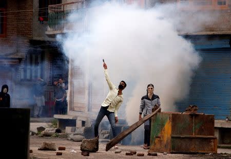 A protester throws a stone amidst smoke from tear gas fired by policemen during a protest in Srinagar against the recent killings in Kashmir, August 29, 2016. REUTERS/Danish Ismail/Files