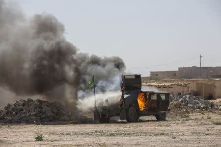 A military vehicle, belonging to Shi'ite fighters known as Hashid Shaabi, burns after being hit by Islamic State militants, during clashes in northern Tikrit, March 11, 2015. REUTERS/Stringer