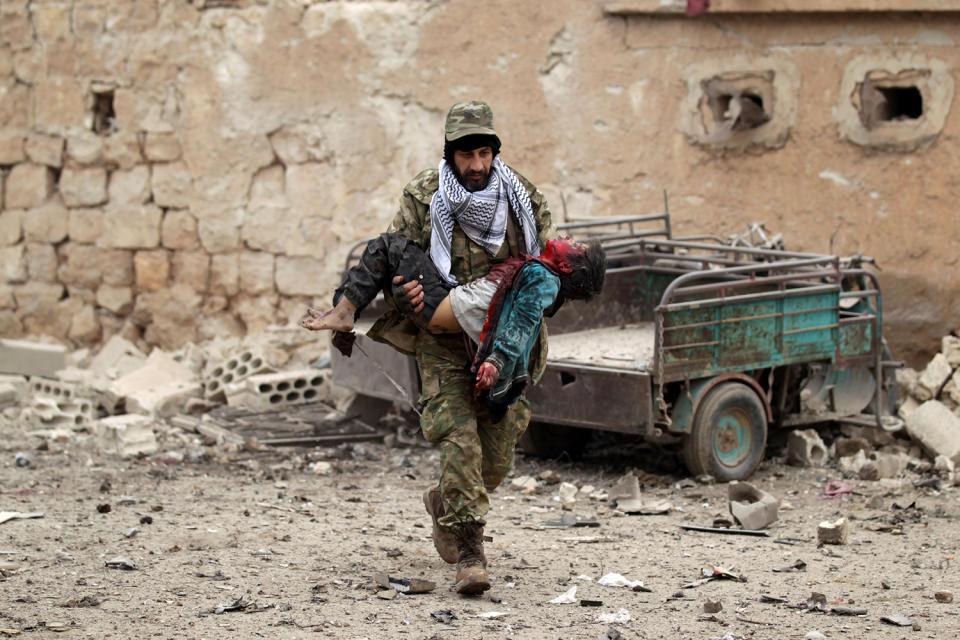 A rebel fighter carries an injured boy after a car bomb explosion in Jub al Barazi east of the northern Syrian town of al-Bab