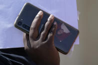 A portrait is seen in a phone case as a migrant arrives at a humanitarian center after they were released from United States Border Patrol upon crossing the Rio Grande and turning themselves in seeking asylum, Wednesday, Sept. 22, 2021, in Del Rio, Texas. (AP Photo/Julio Cortez)