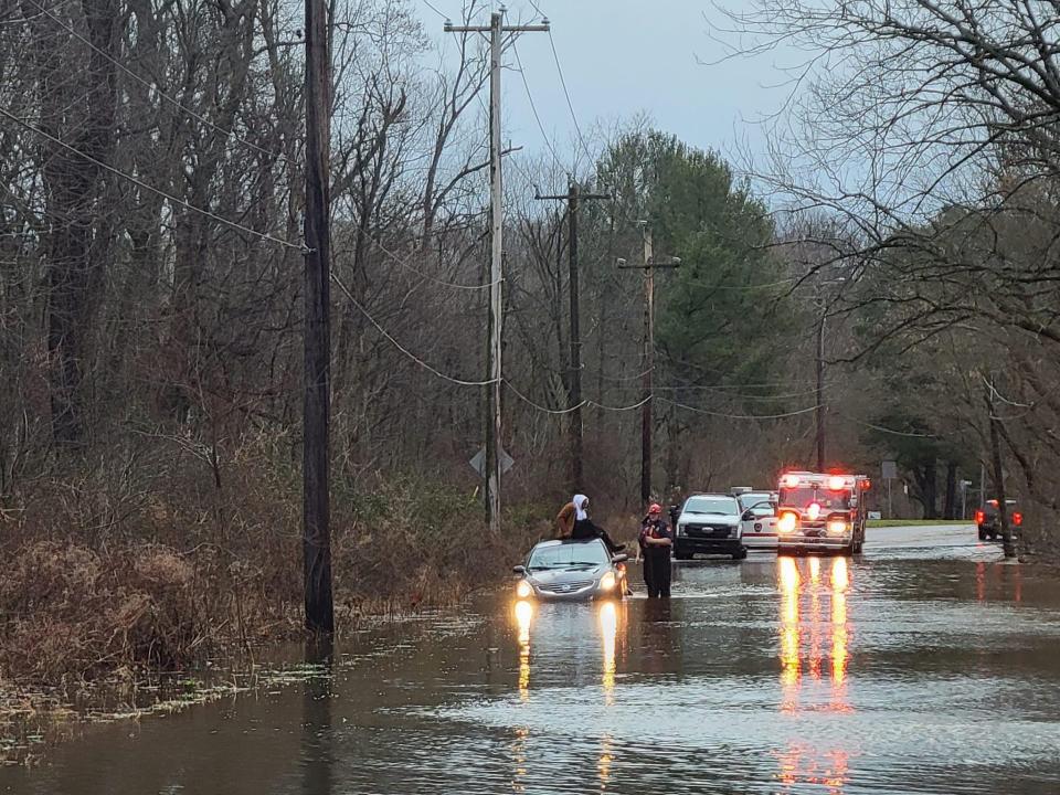 A motorist sits on top of his car after entering flood waters at Route 413 and Winchester Avenue in Middletown after a storm that dumped up to four inches of rain on Bucks County. Officials urged motorists not to ignore barricades and enter flooded roads.