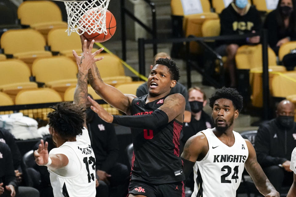 Houston guard Marcus Sasser, center, gets between Central Florida guard Brandon Mahan (13) and guard Dre Fuller Jr. (24) for a shot during the second half of an NCAA college basketball game, Saturday, Dec. 26, 2020, in Orlando, Fla. (AP Photo/John Raoux)