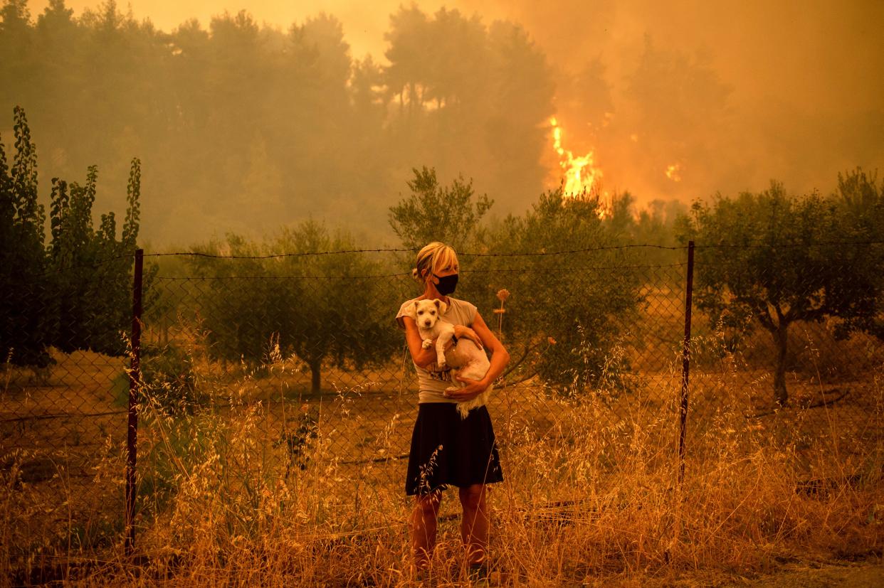 A woman holds a dog in her arms as forest fires approach the village of Pefki on Evia (Euboea) island, Greece's second-largest island, on Aug. 8.