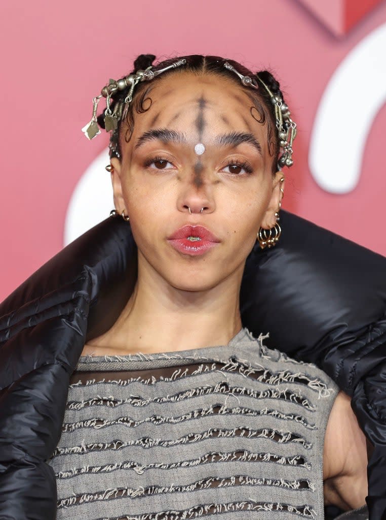 FKA Twigs in a metallic dress and puffy jacket at an event