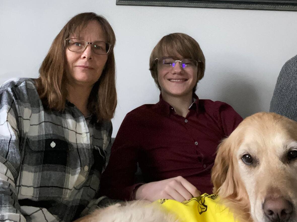 Rhonda Pigeon and her son Gabriel, 16, with his buddy dog, Maggie. Gabriel is legally blind and says he has trouble getting large print materials in a timely fashion from his Calgary high school. (Submitted by Rhonda Pigeon - image credit)