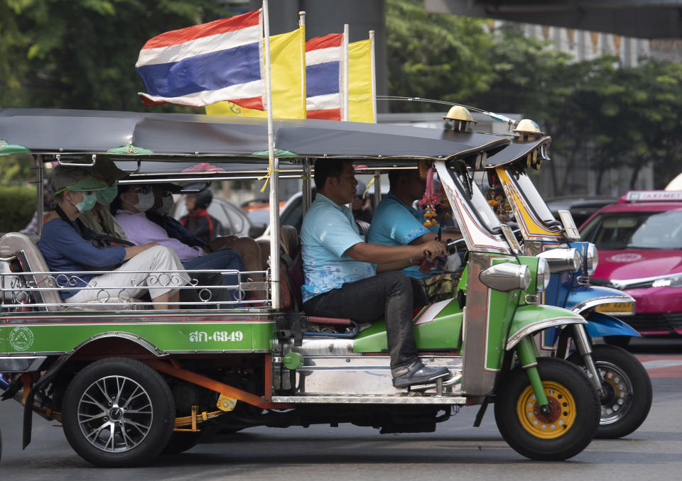 Tourists ride in tuk-tuks wearing face masks to protect from the poor air quality in Bangkok, Thailand, Monday, Jan. 20, 2020. Thick haze blanketed the Thai capital on Monday sending air pollution levels soaring to 89 micrograms per cubic meter of PM2.5 particles in some areas, according to the Pollution Control Department. (AP Photo/Sakchai Lalit)