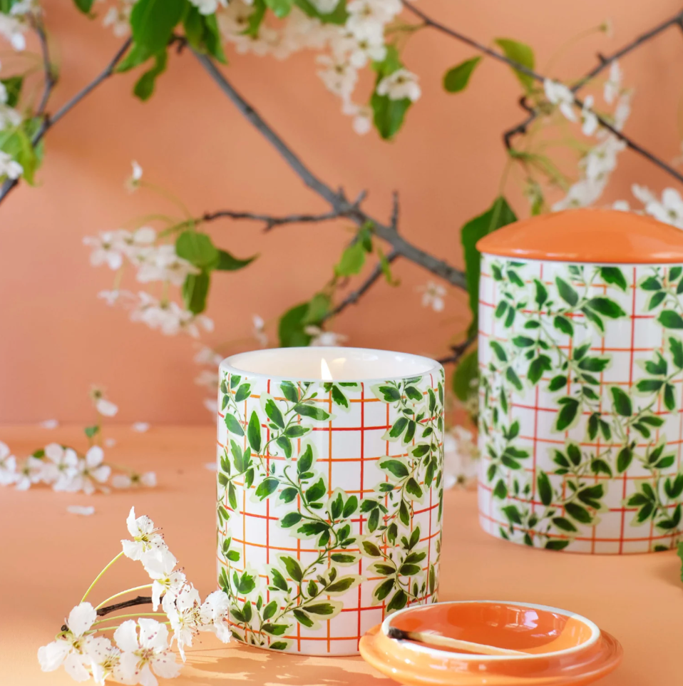 two candles in ceramic jars with ivy motifs