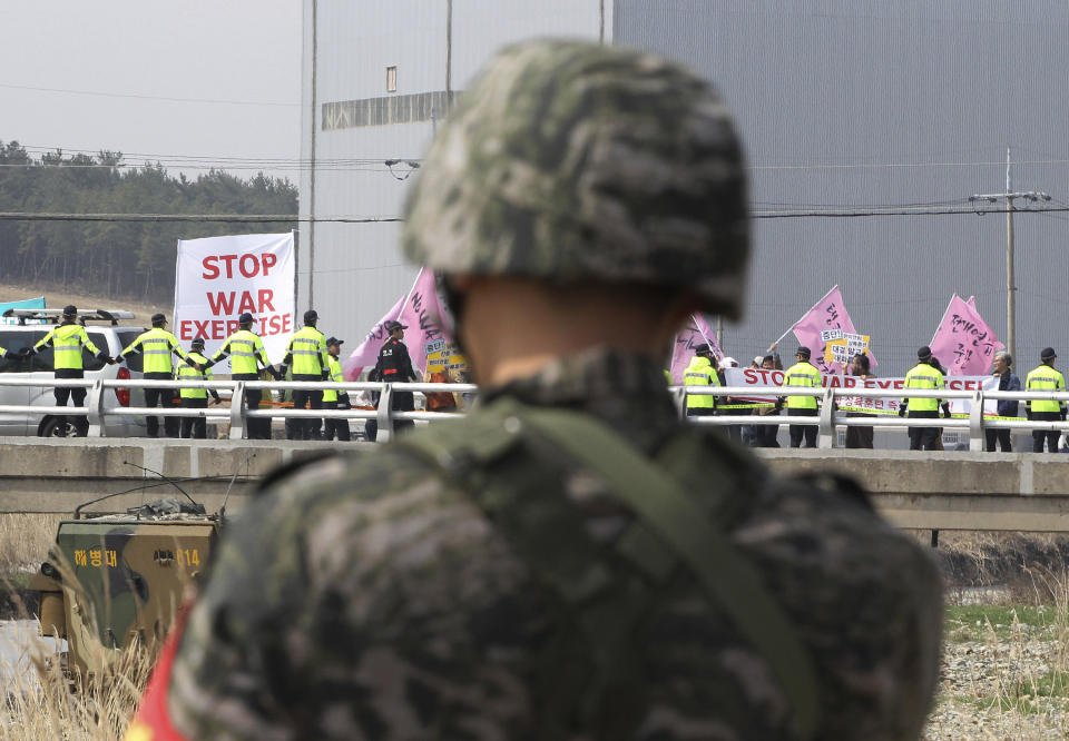 A South Korean marine watches anti-war protesters stage a rally during the U.S.-South Korea joint landing exercises called Ssangyong, part of the Foal Eagle military exercises, in Pohang, South Korea, Monday, March 31, 2014. (AP Photo/Ahn Young-joon)