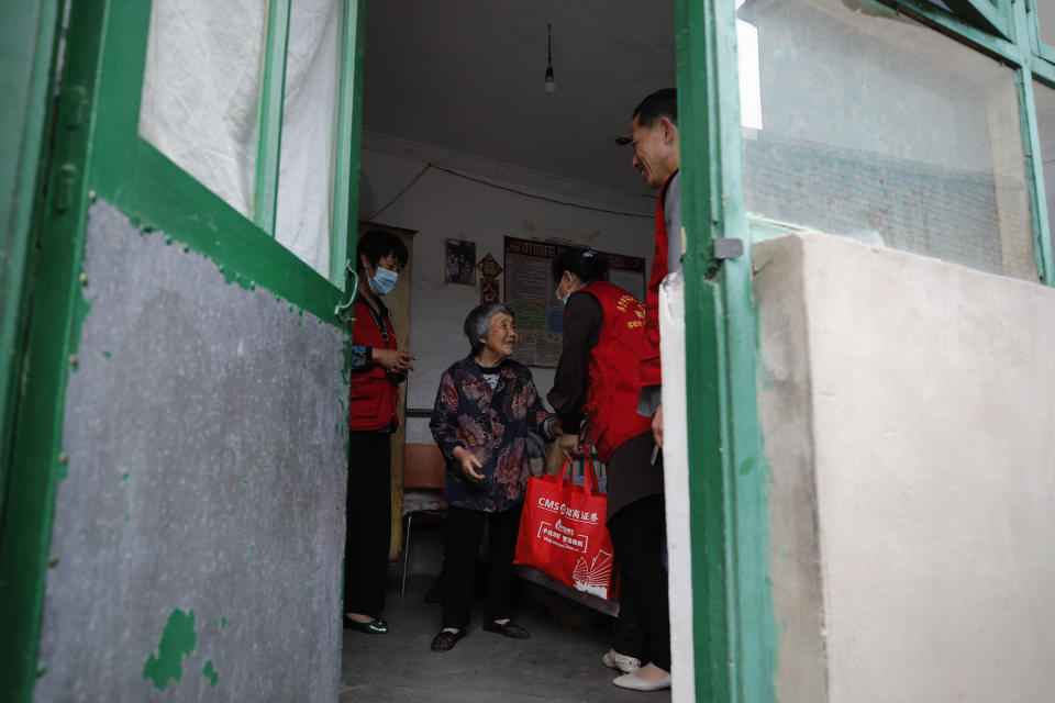 Kang Yuxia, right, and his volunteers deliver a free vegetarian meal to an elderly woman in Dingxing, southwest of Beijing on May 13, 2021. China's leaders are easing limits on how many children each couple can have, hoping to counter the rapid aging of Chinese society. (AP Photo/Andy Wong)